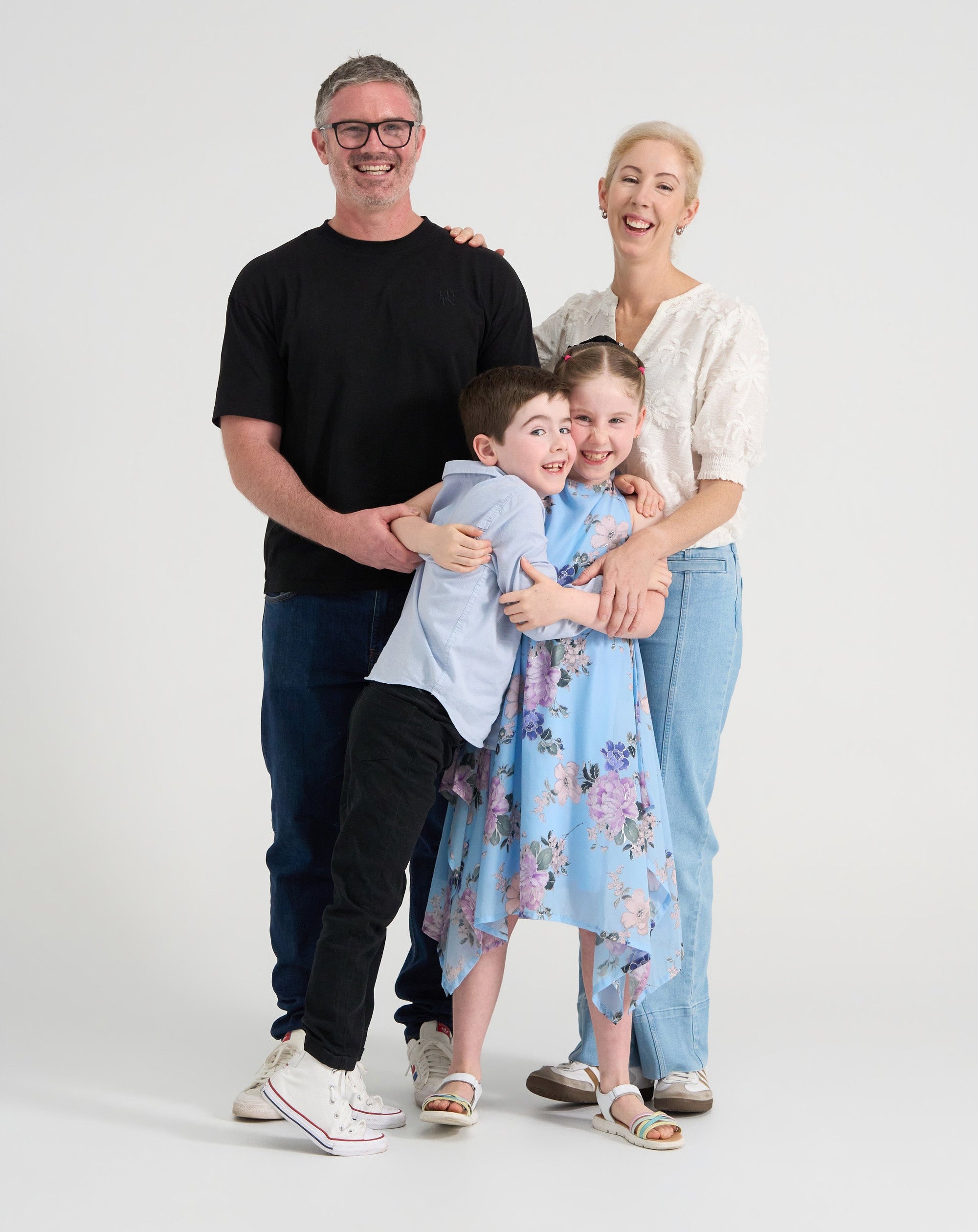 Family of four standing together on a white background